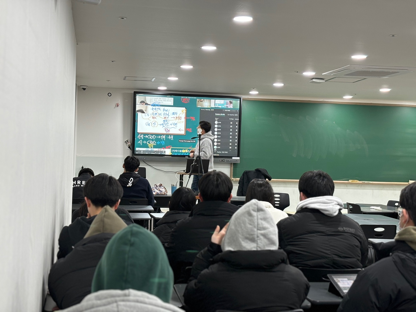 전자칠판에 클래스인 수업 화면을 띄워 놓고 설명하는 강사와 학생들